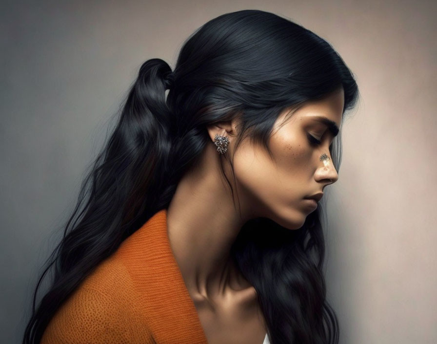 Profile of woman with long dark hair, orange top, elegant earring, golden glitter.