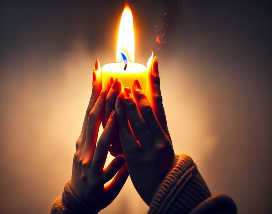 Hands Holding Lit Candle with Sparks Against Dark Background