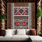Patterned tapestry above white sofa and green plants on wood-paneled wall
