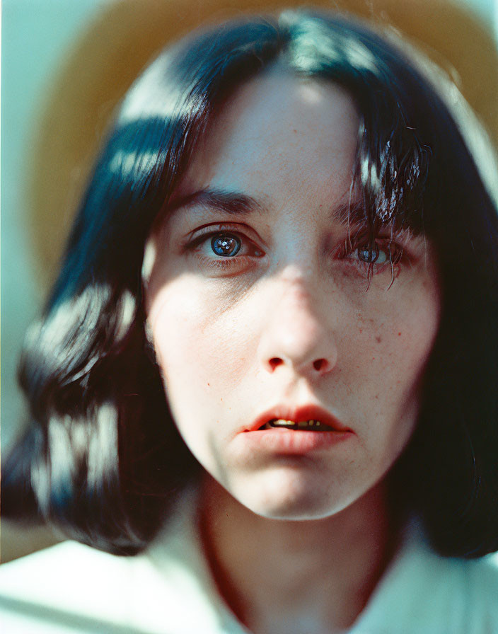 Portrait of woman with deep blue eyes, dark hair, and freckles in contemplation
