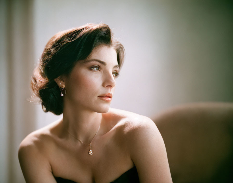 Portrait of woman with short dark hair in strapless dress and jewelry.