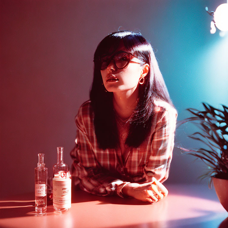 Dark-haired woman with glasses at pink table in dimly lit room
