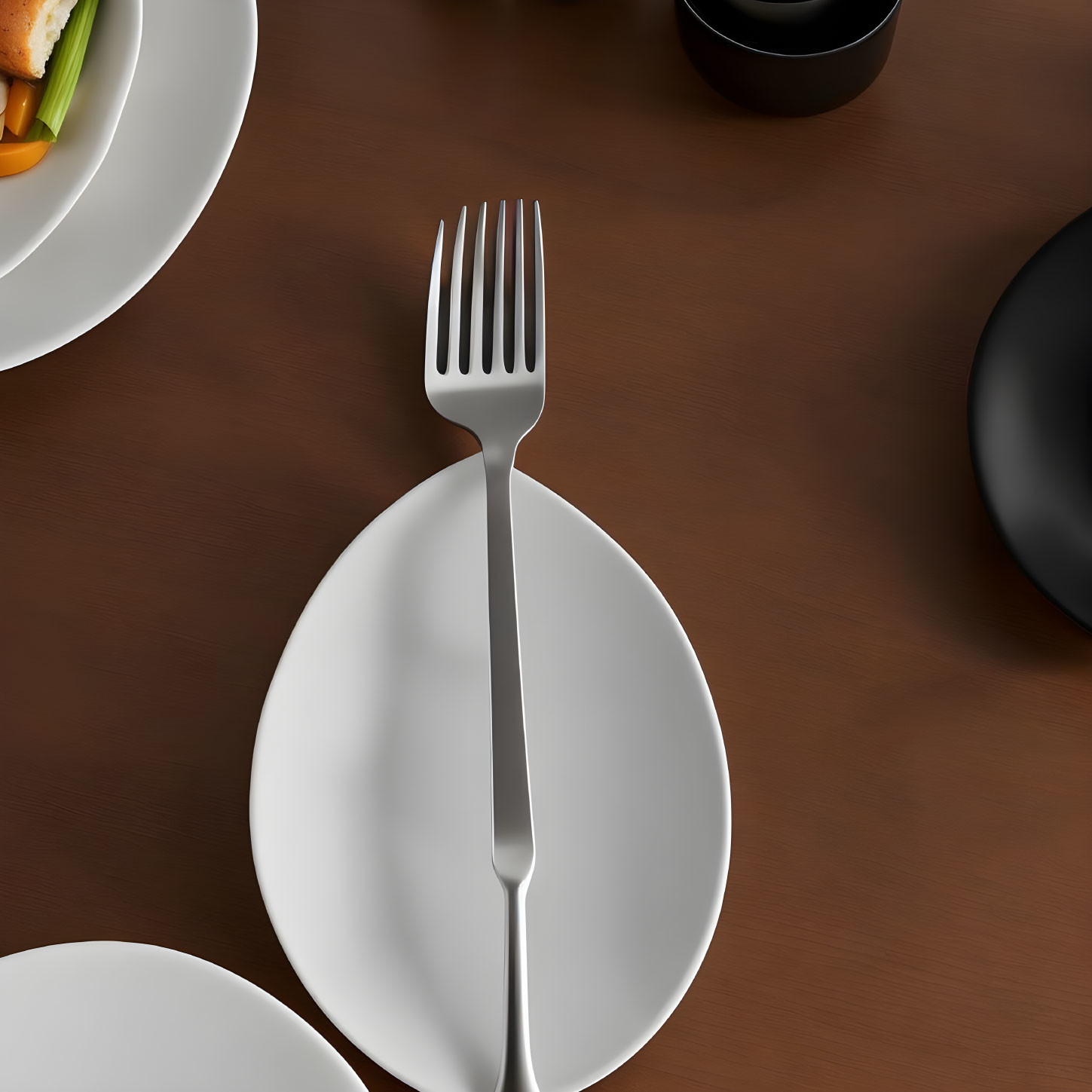 Metal fork on white plate in modern table setting with dishes and cup