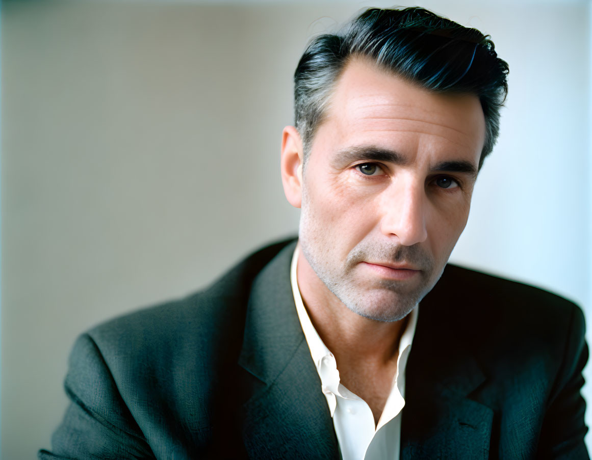 Dark-haired man in stylish suit and open-collared shirt with confident gaze