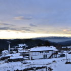Snowy Village at Winter Sunrise with Warmly Lit Houses