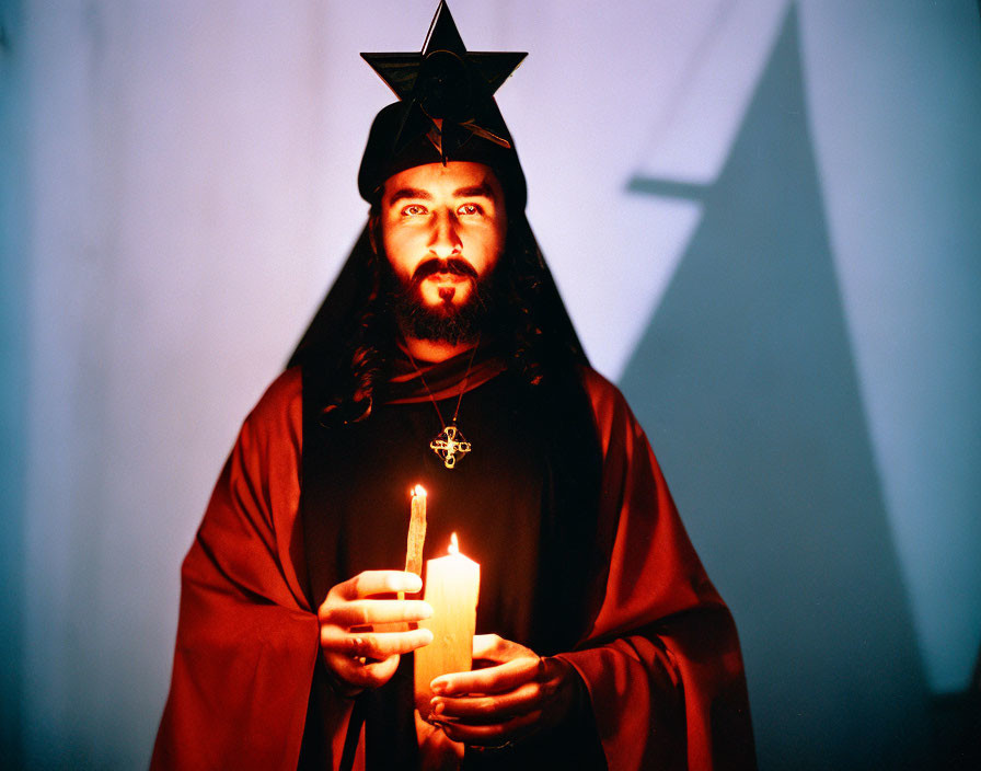 Bearded person in red robe with star headpiece holding candle by star shadow