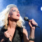 Blonde Curly-Haired Singer on Stage with Microphone
