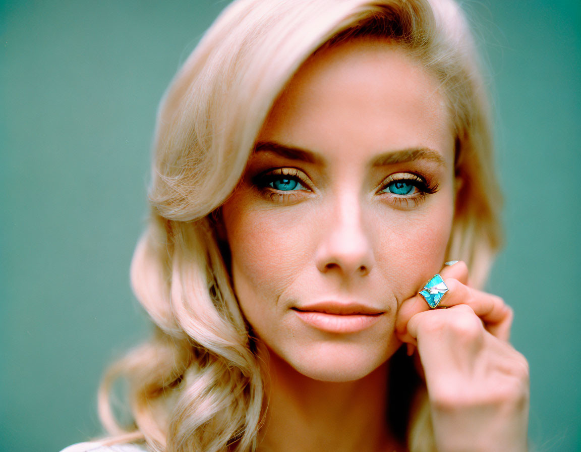Blonde Woman with Blue Eyes Holding Turquoise Ring on Green Background