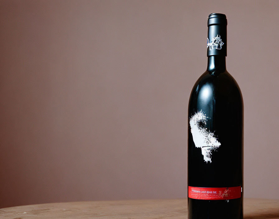 Dark wine bottle with white and red label on wooden surface