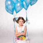Stylized illustration of young girl with blue balloons and hearts