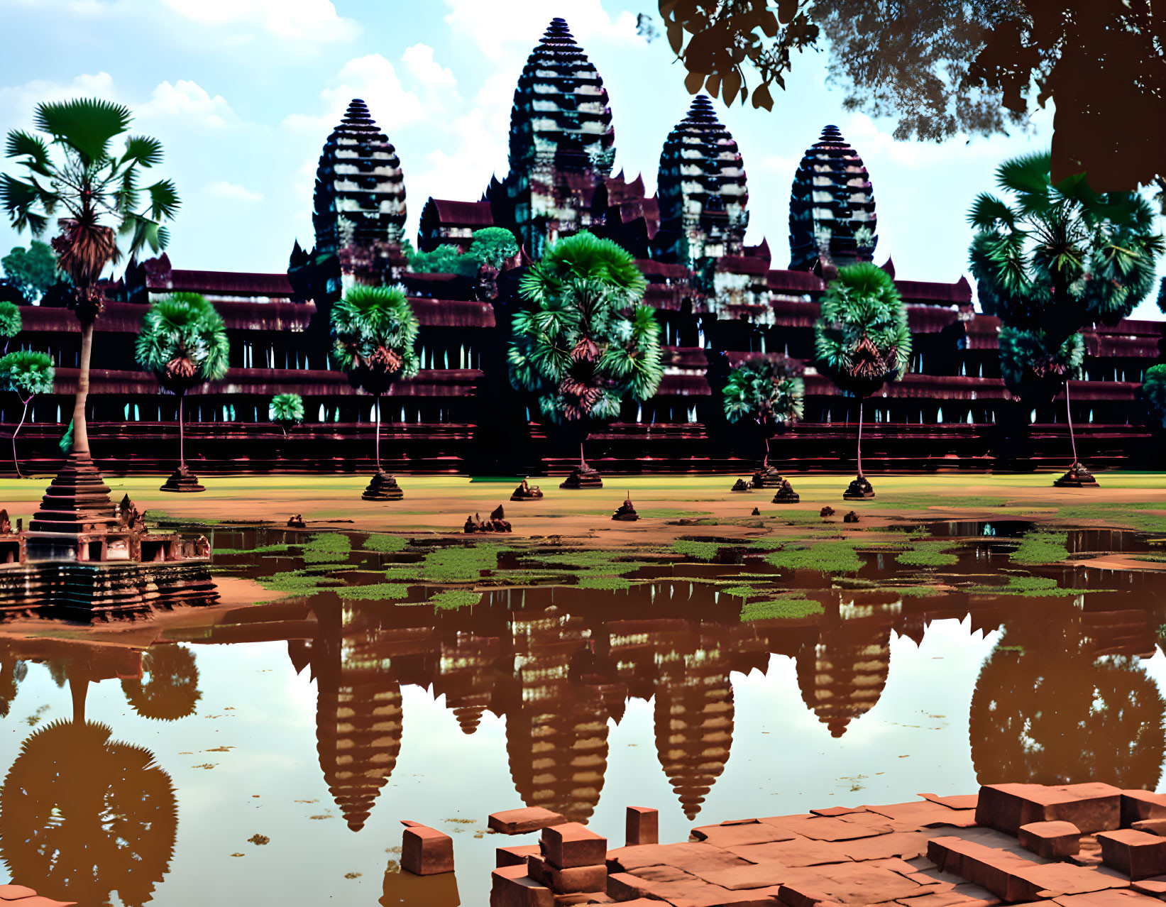 Majestic Angkor Wat temple complex with water reflection and tropical surroundings