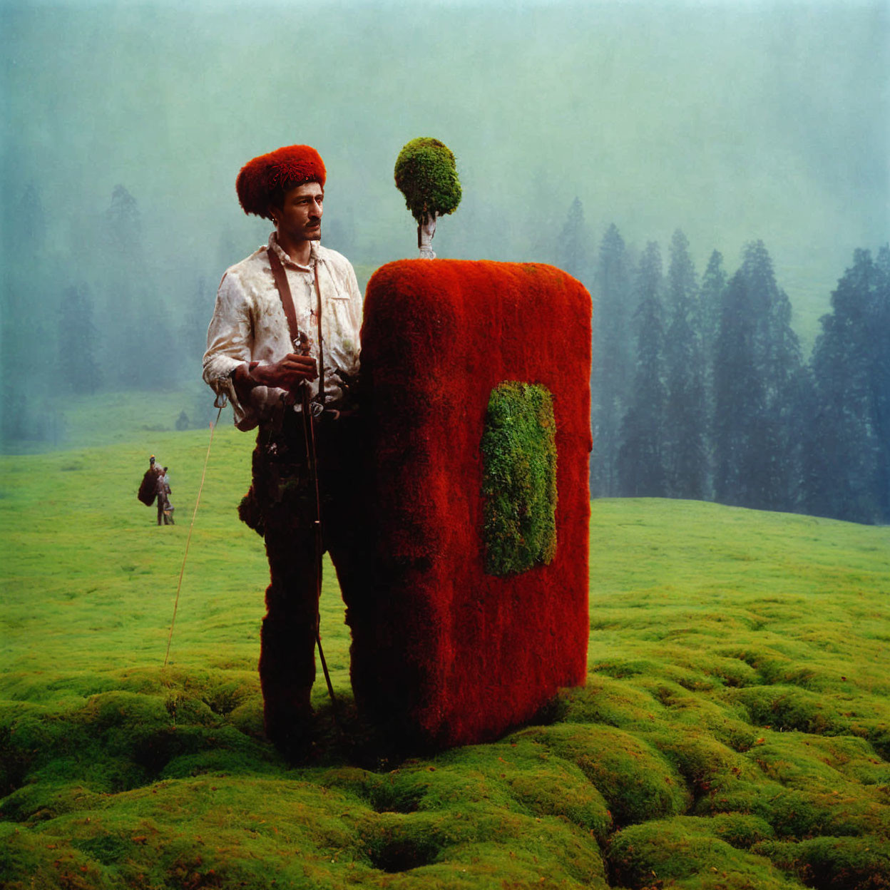 Traditional Attire Man with Moss-Covered Book-Like Object in Green Field