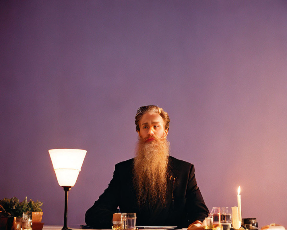 Bearded man in suit at dining table with candles, lamp, and plants