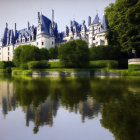 Majestic chateau with pointed roofs reflected in calm waters amid lush greenery