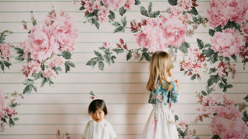A little girl admiring floral wallpaper