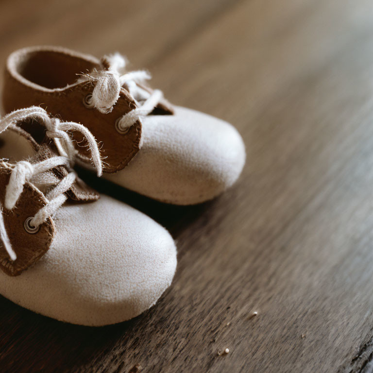 Soft Off-White Baby Shoes with Laces on Wooden Surface