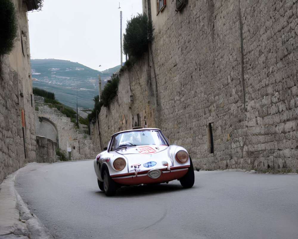 Vintage Race Car on Cobblestone Street with Stone Walls and Hills