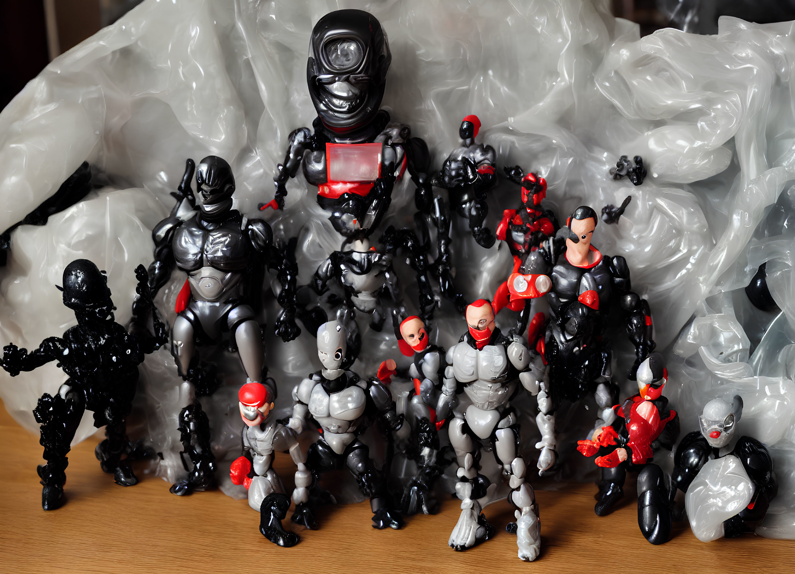 Assorted black, red, and grey action figures on wooden surface with plastic bags