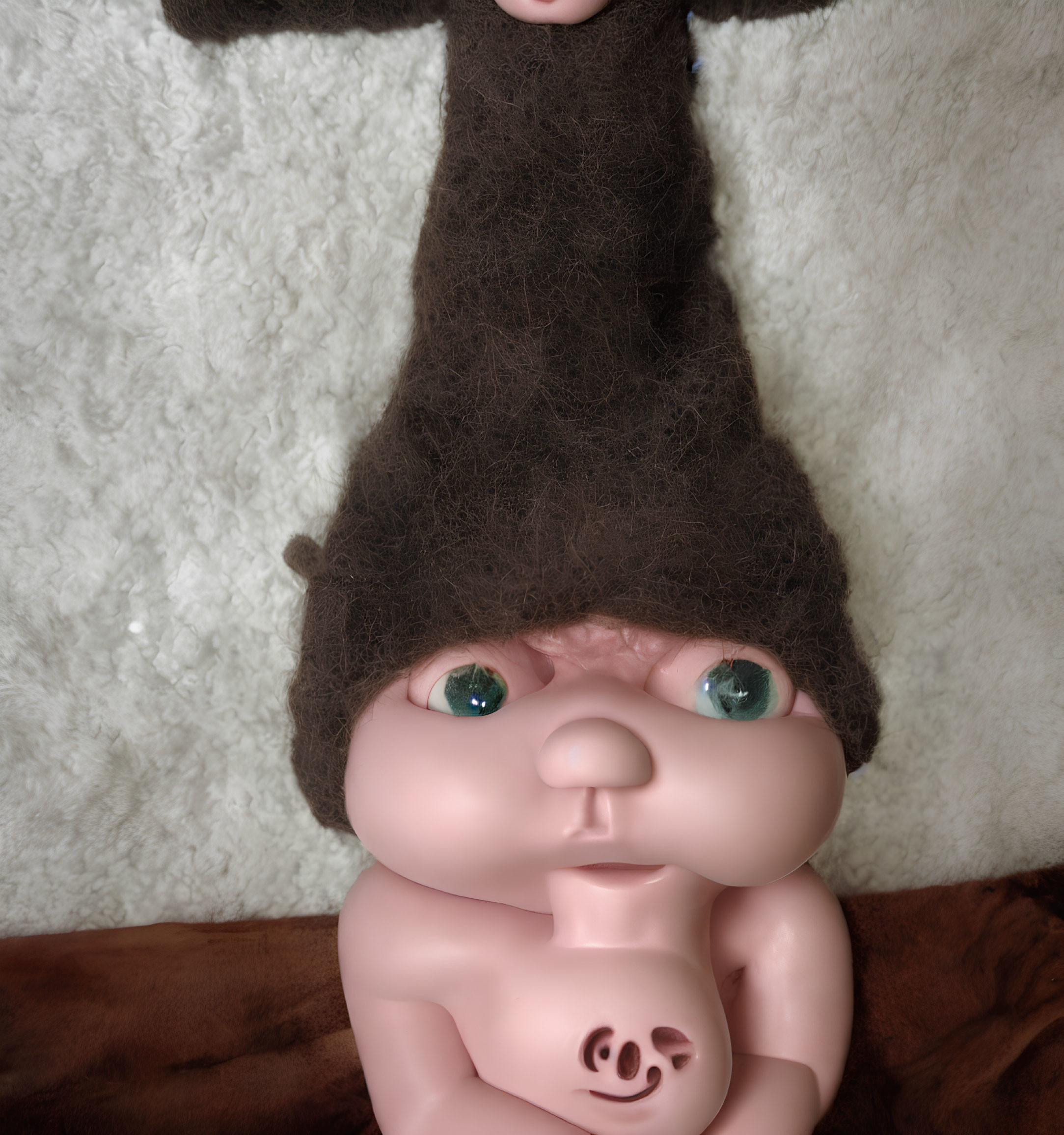 Exaggerated features doll with pointy hairdo and green eyes on white and brown background