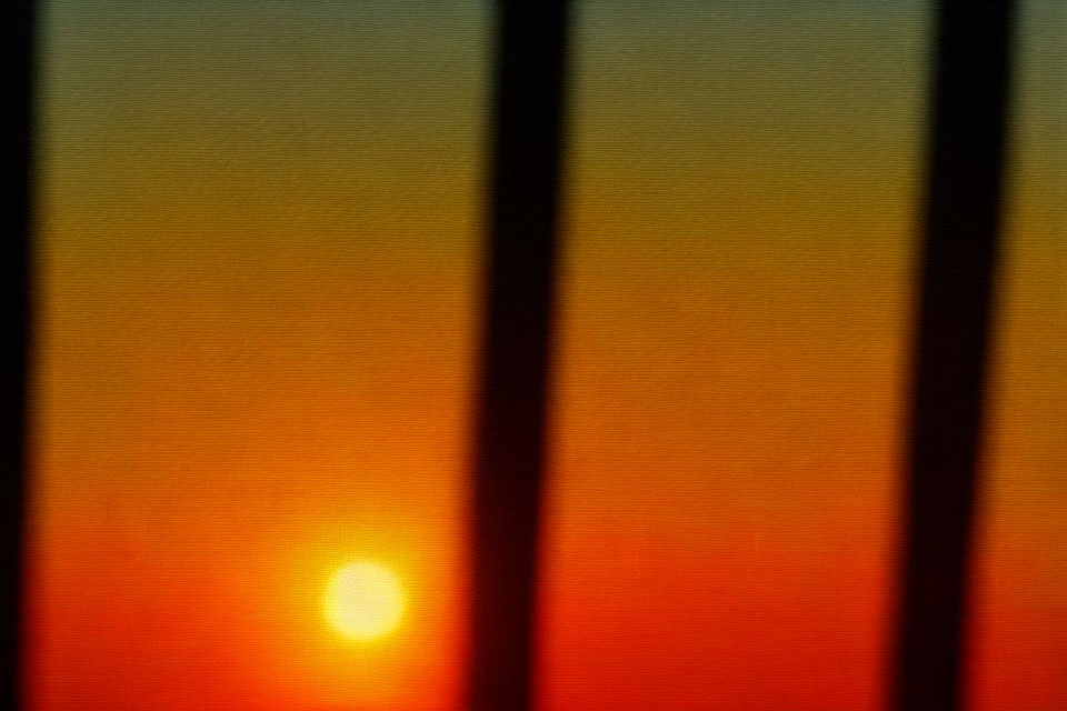 Scenic sunset view through window blinds on orange sky