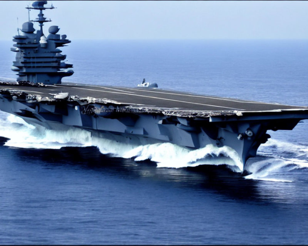 Military aircraft carrier with flight deck and island superstructure at sea