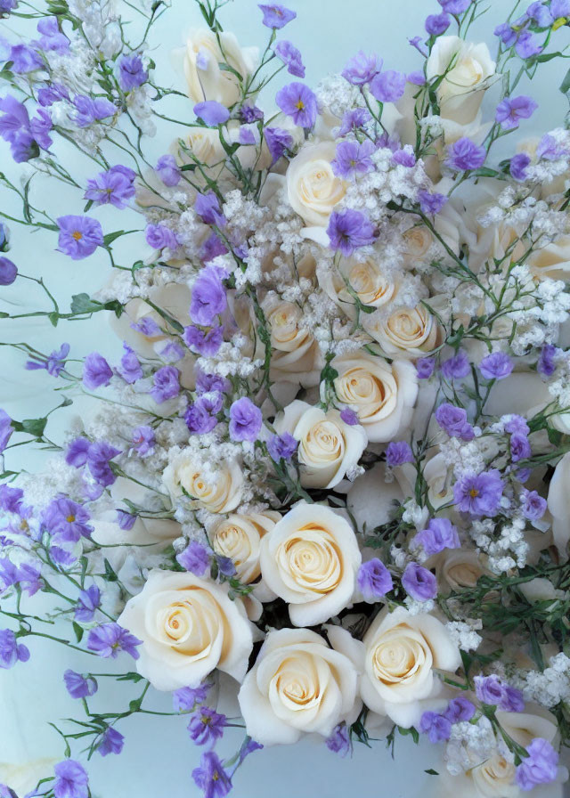 White Roses, Purple Flowers, and Baby's Breath Bouquet on Pale Background