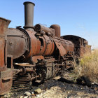 Steampunk-style train on railway with cogwheel trees under blue sky