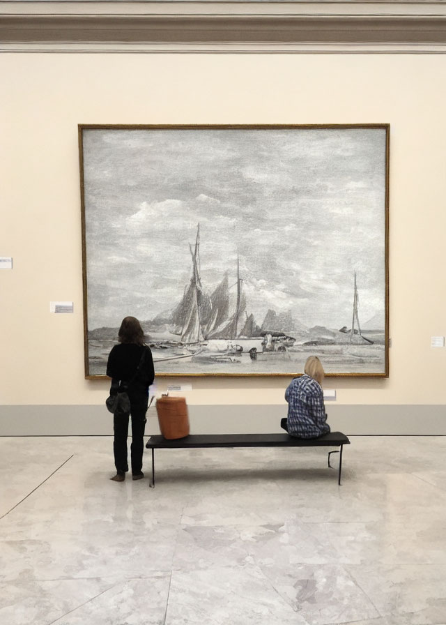 Gallery scene with two people viewing monochrome sailing ships painting