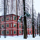 Snow-covered red-brick building and trees in serene winter scene