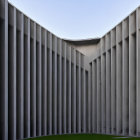 Modern Concrete Building with Vertical Lines and Tree in Soft Sunlight