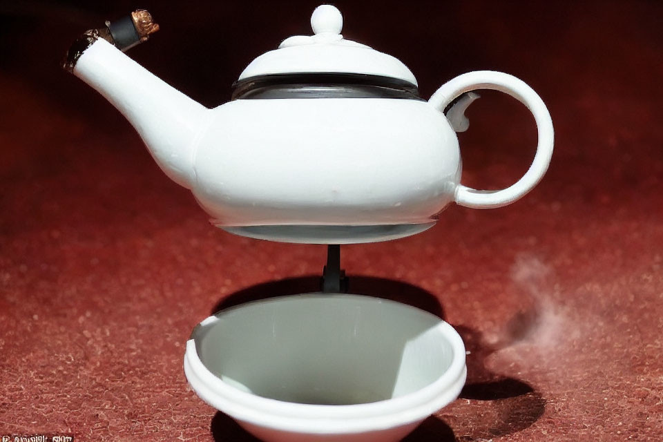 Levitating white ceramic teapot with steam above matching cup on red surface