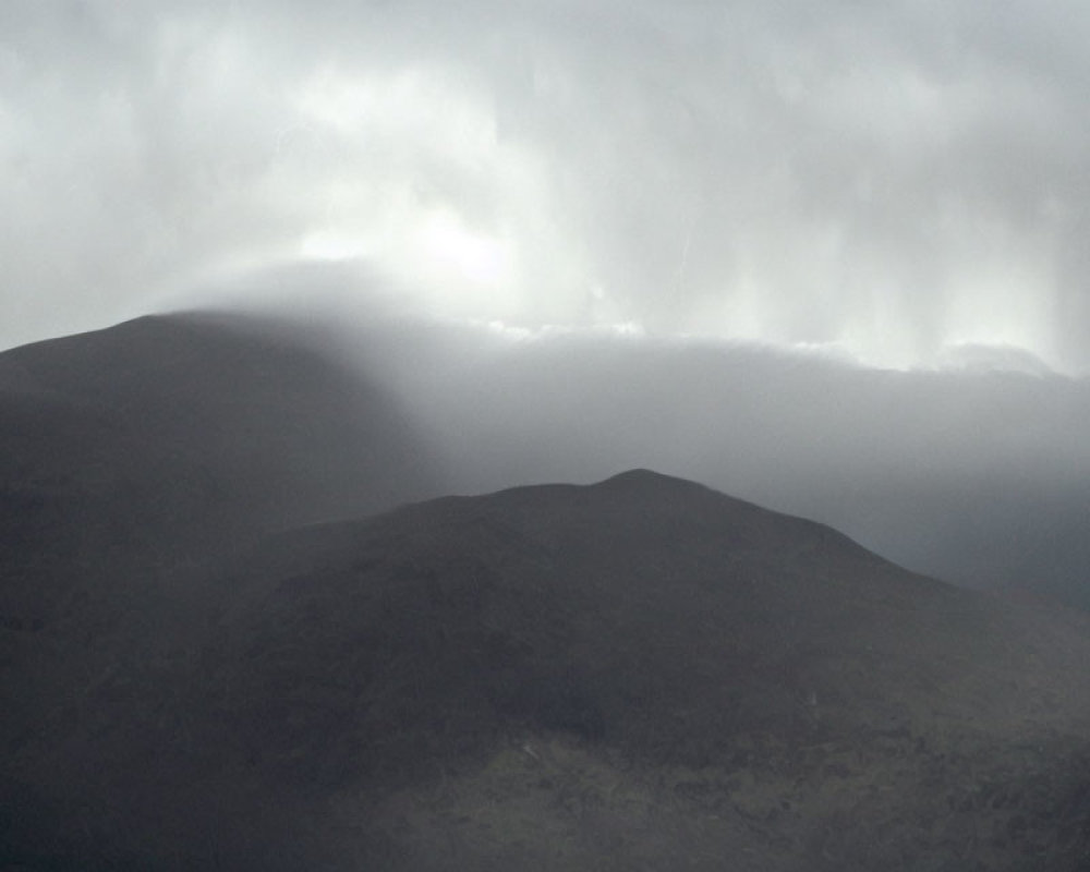 Moody landscape with dark hills under overcast sky