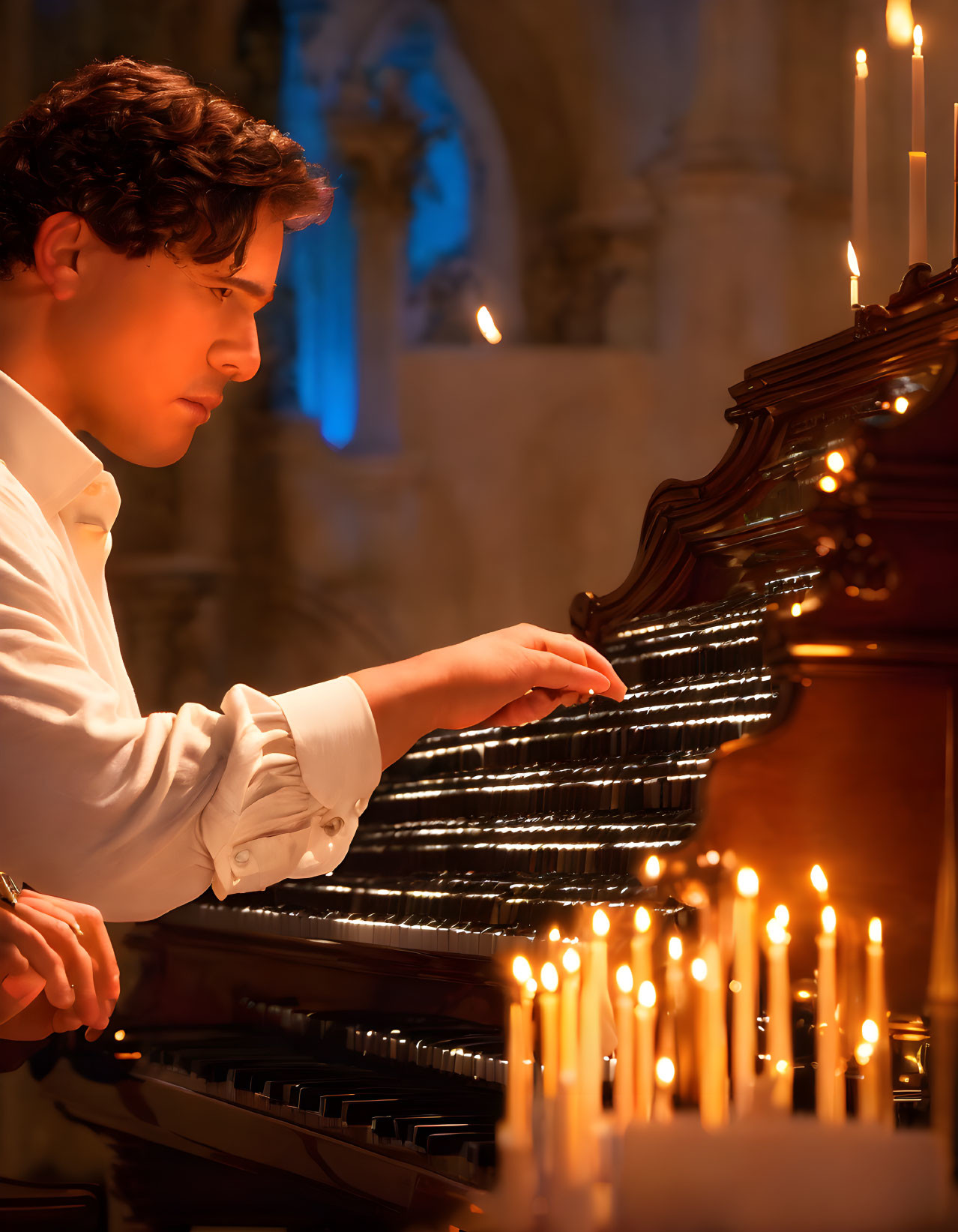 Young man playing grand piano in candlelit room with classical architecture