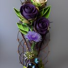 Cream and purple rose bouquet with blue thistle and wirework accents.