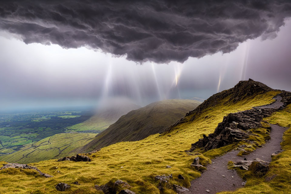 Dramatic mountain path under stormy sky with sunbeams piercing through clouds