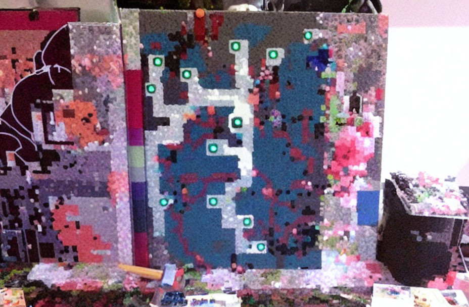 Pixelated colorful digital map art surrounded by various artwork and clutter in foreground