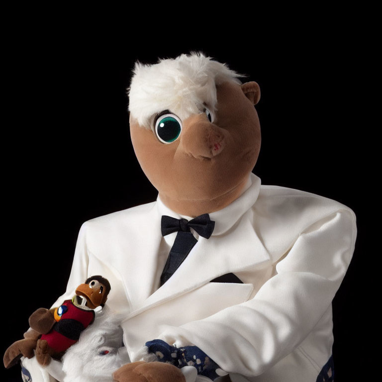 Eagle puppet in white tuxedo with miniature puppet on hand against black background