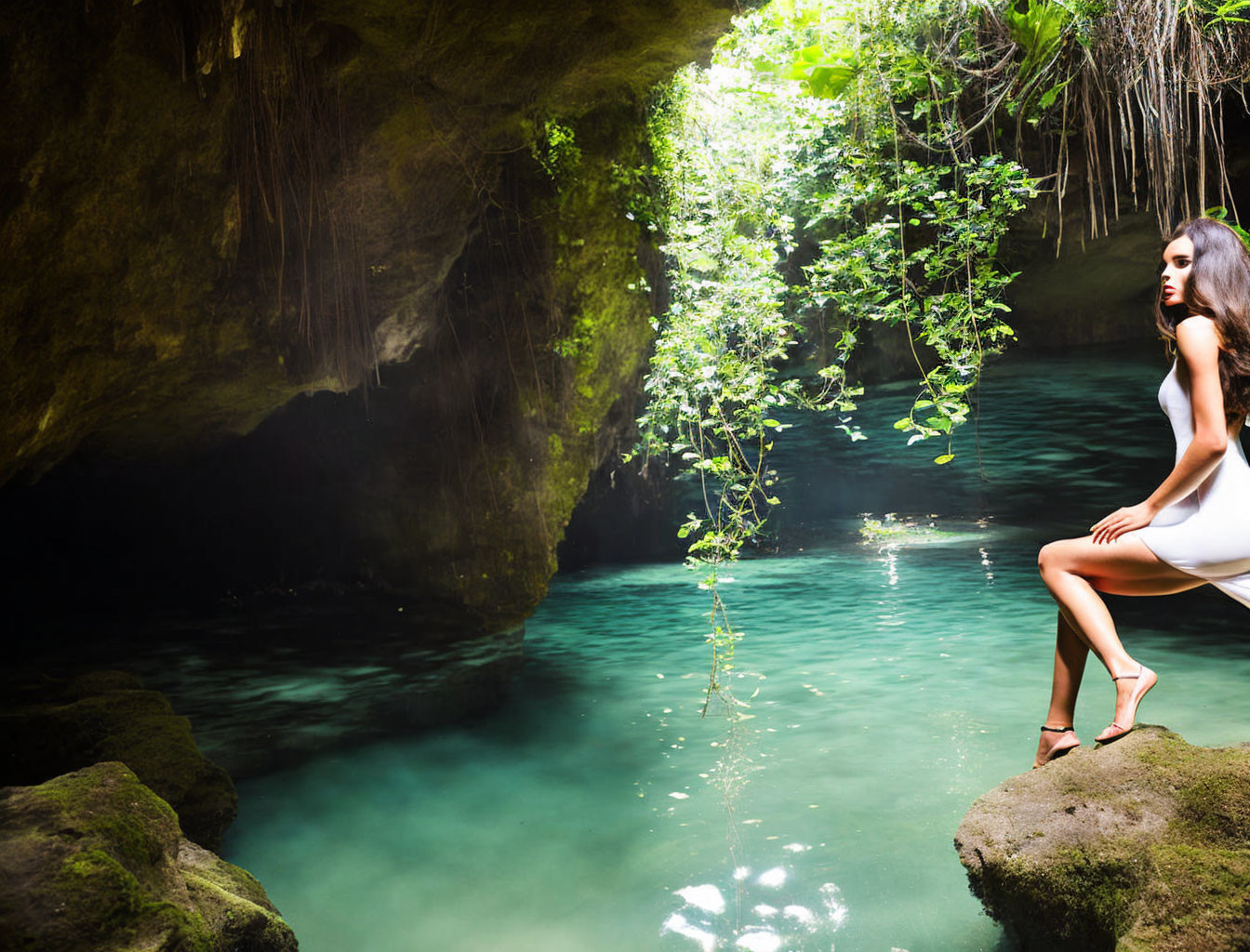 Woman in White Dress Sitting by Emerald Green Cave Pool