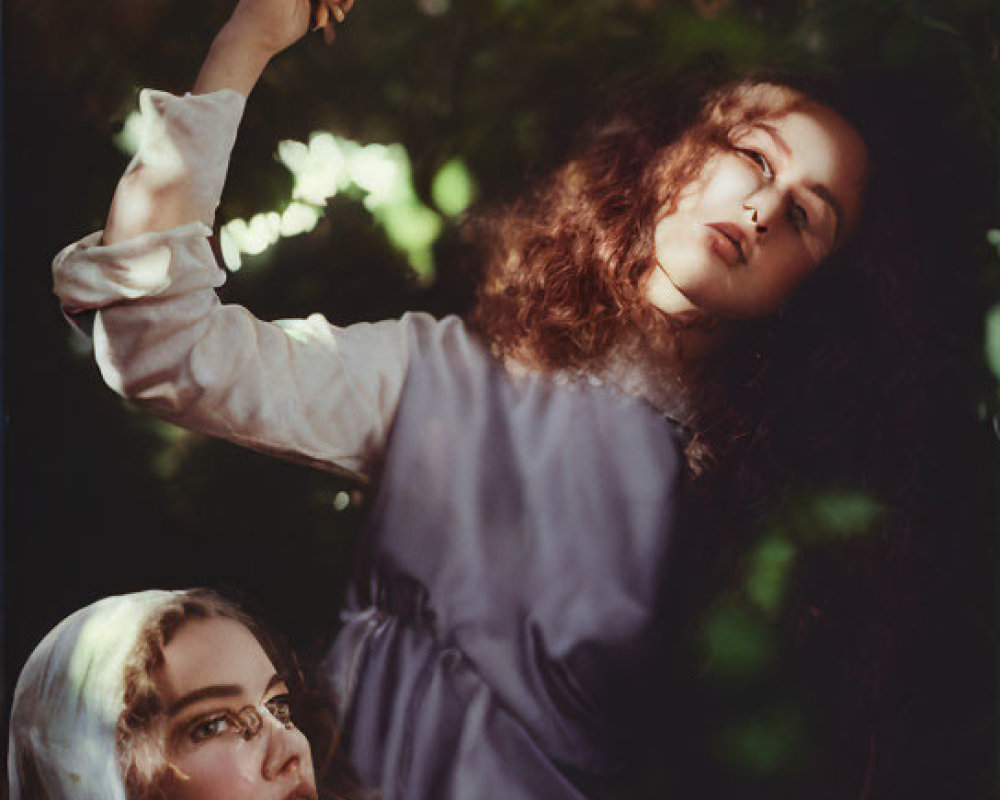 Vintage Attired Women with Camera in Dappled Light Amidst Foliage