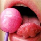 Pink glossy lips with small bubble gum balloon close-up.