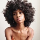 Woman with Voluminous Afro Hair and Pink Top in Hoop Earrings