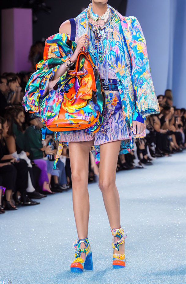 Fashion model showcasing vibrant, patterned outfit and statement accessories on a colorful runway