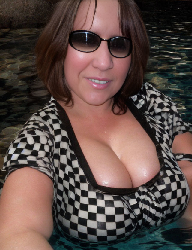 Woman in black and white checkered swimsuit smiling in pool