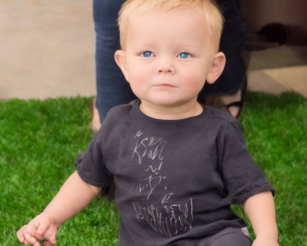 Blonde Toddler with Blue Eyes Sitting on Grass