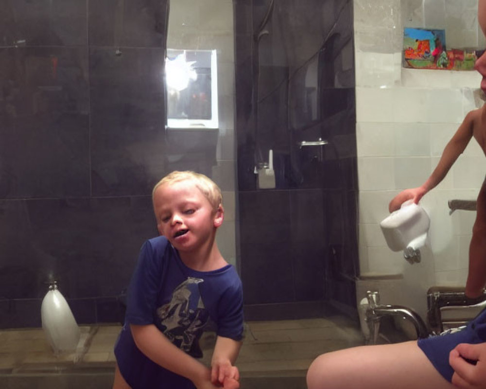 Two boys in bathroom, one on toilet, other on bench with toothbrush, looking off-screen