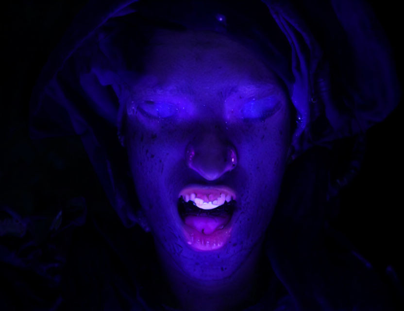 Portrait of person with closed eyes under haunting blue light