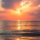 Tranquil sunset beach scene with orange and yellow hues on calm sea