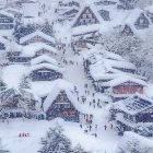 Snow-covered village scene with wintry houses, trees, and people bundled up