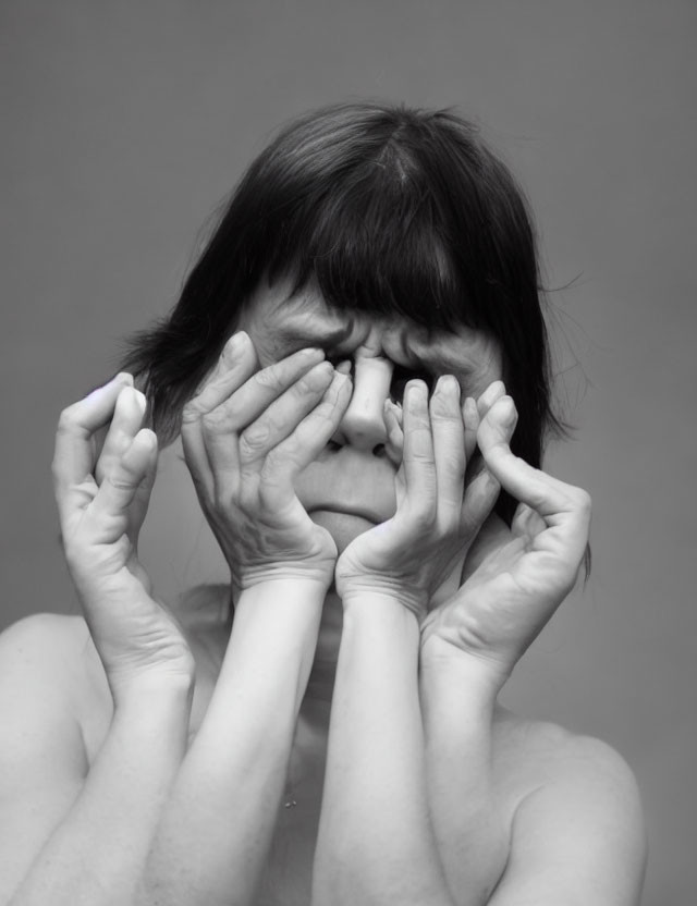 Monochrome portrait of person looking through fingers as glasses