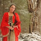 Woman in red cloak and dress with wreath in snowy pine forest